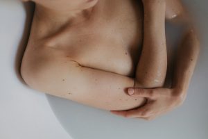 A serene moment of a person relaxing topless in a bathtub, captured with soft lighting.