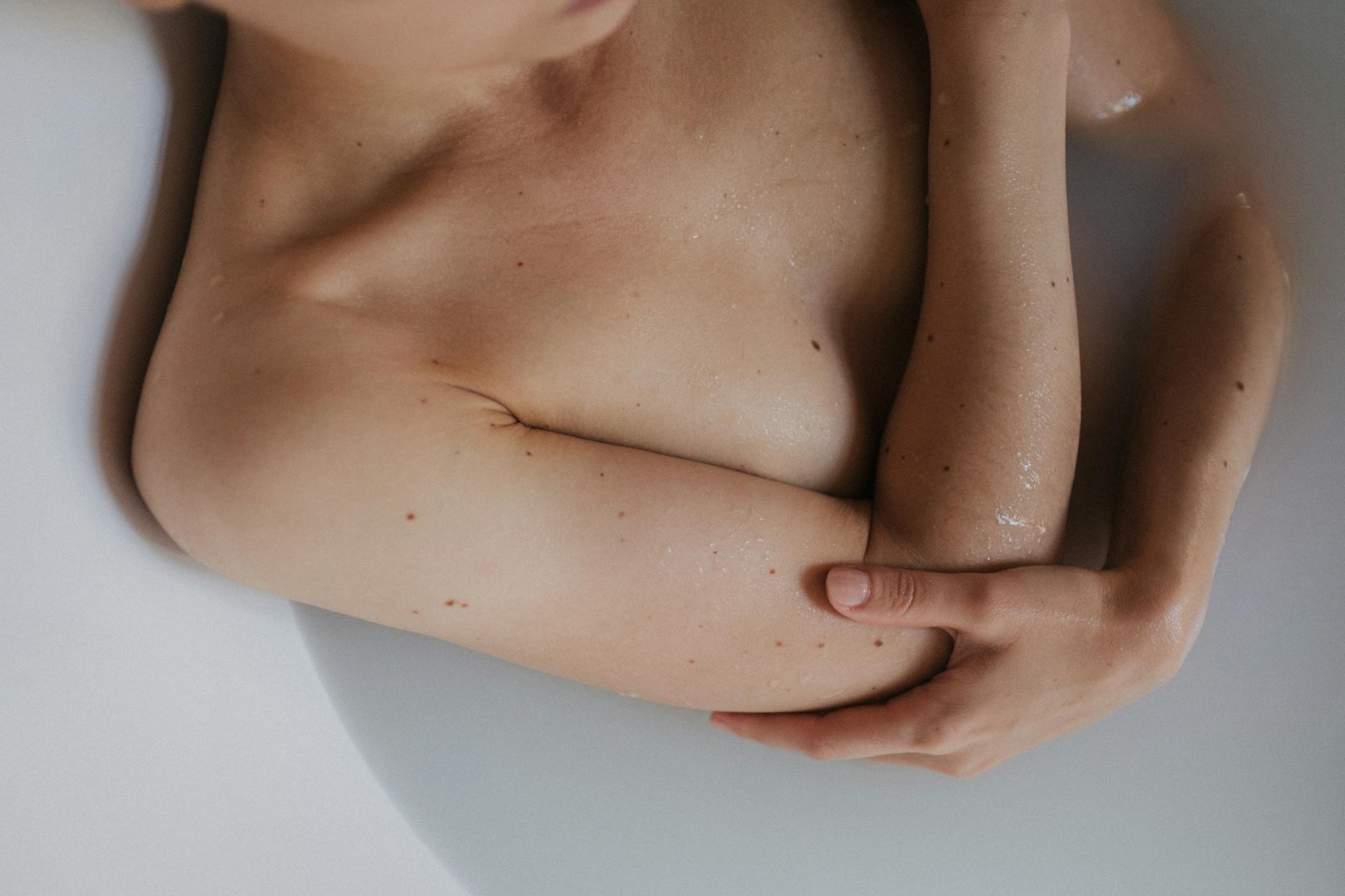 A serene moment of a person relaxing topless in a bathtub, captured with soft lighting.