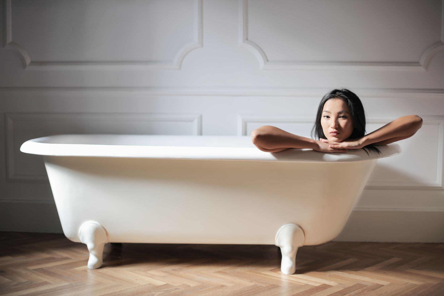 A woman enjoying a relaxing moment in a minimalistic white bathtub, embracing tranquility.